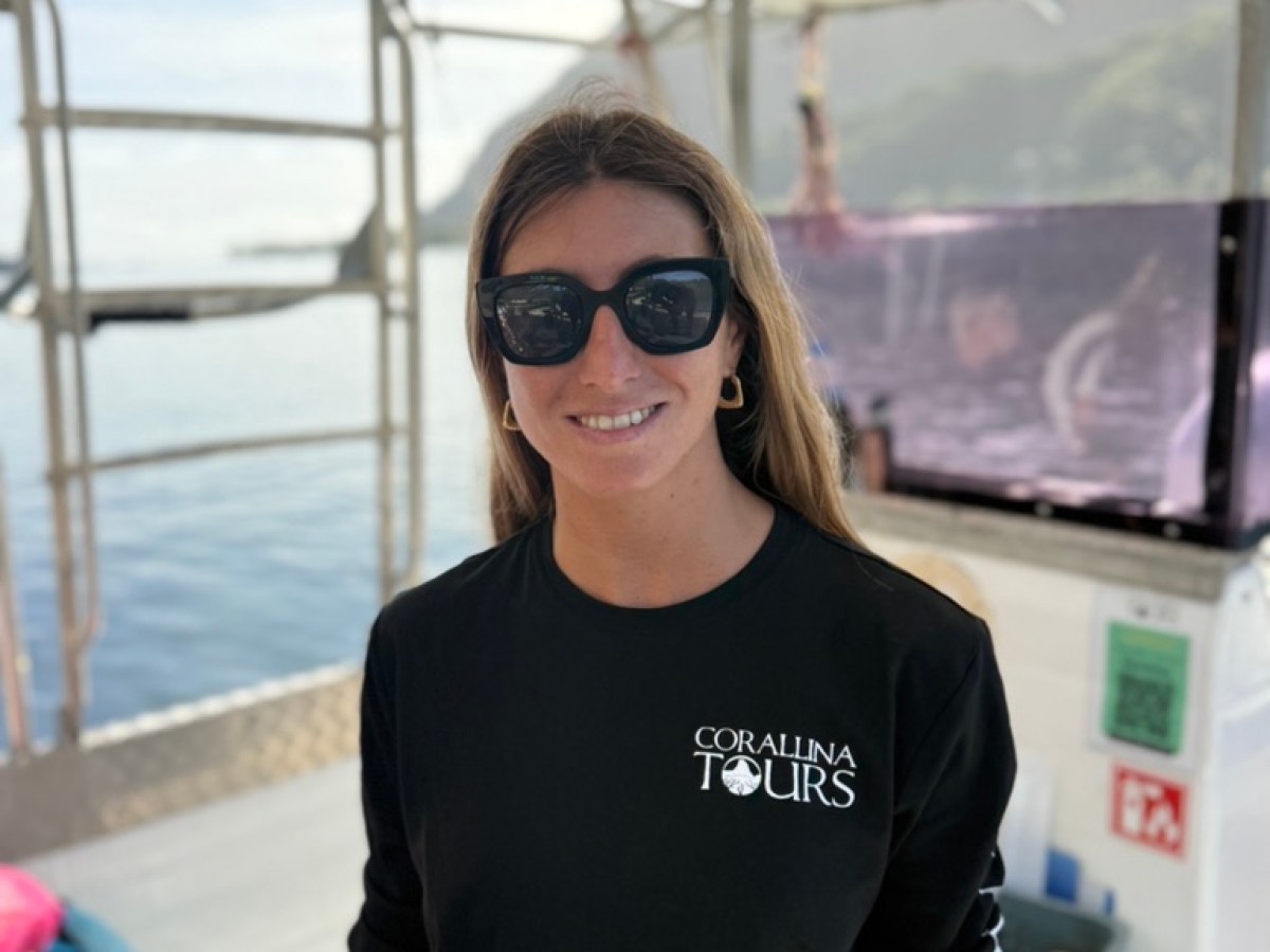Person in sunglasses and black shirt on a boat with ocean in the background.